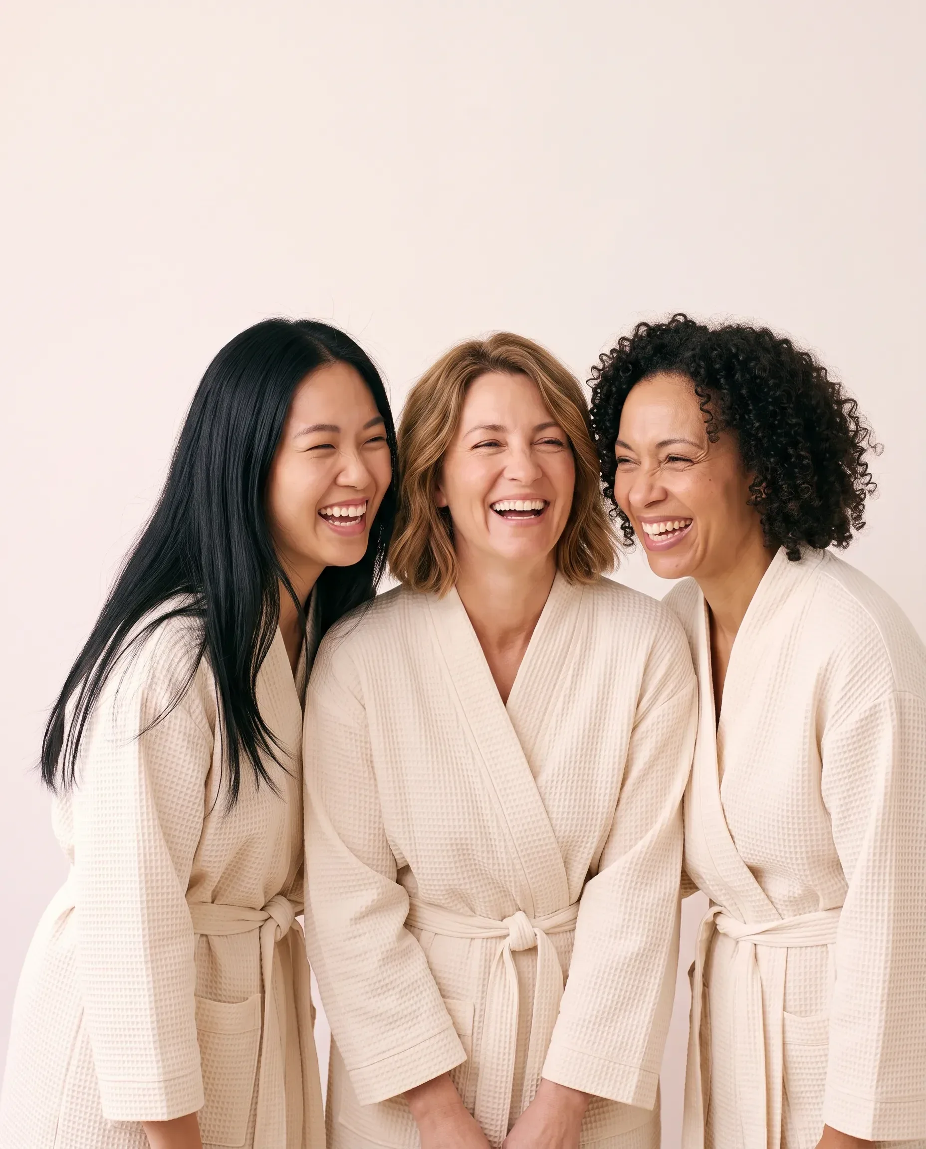 Three Beauty Bank members laughing together in spa robes